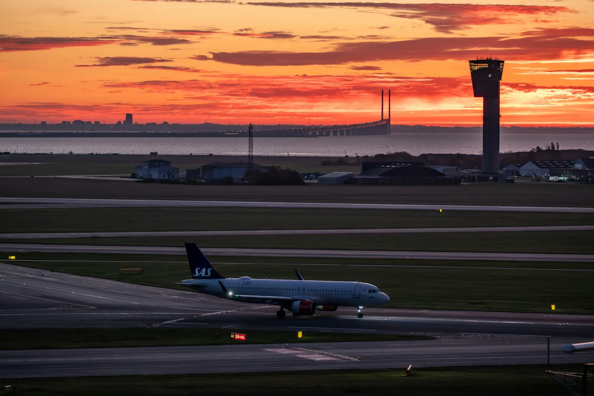 Aircraft positioned near a runway under a warm evening sky