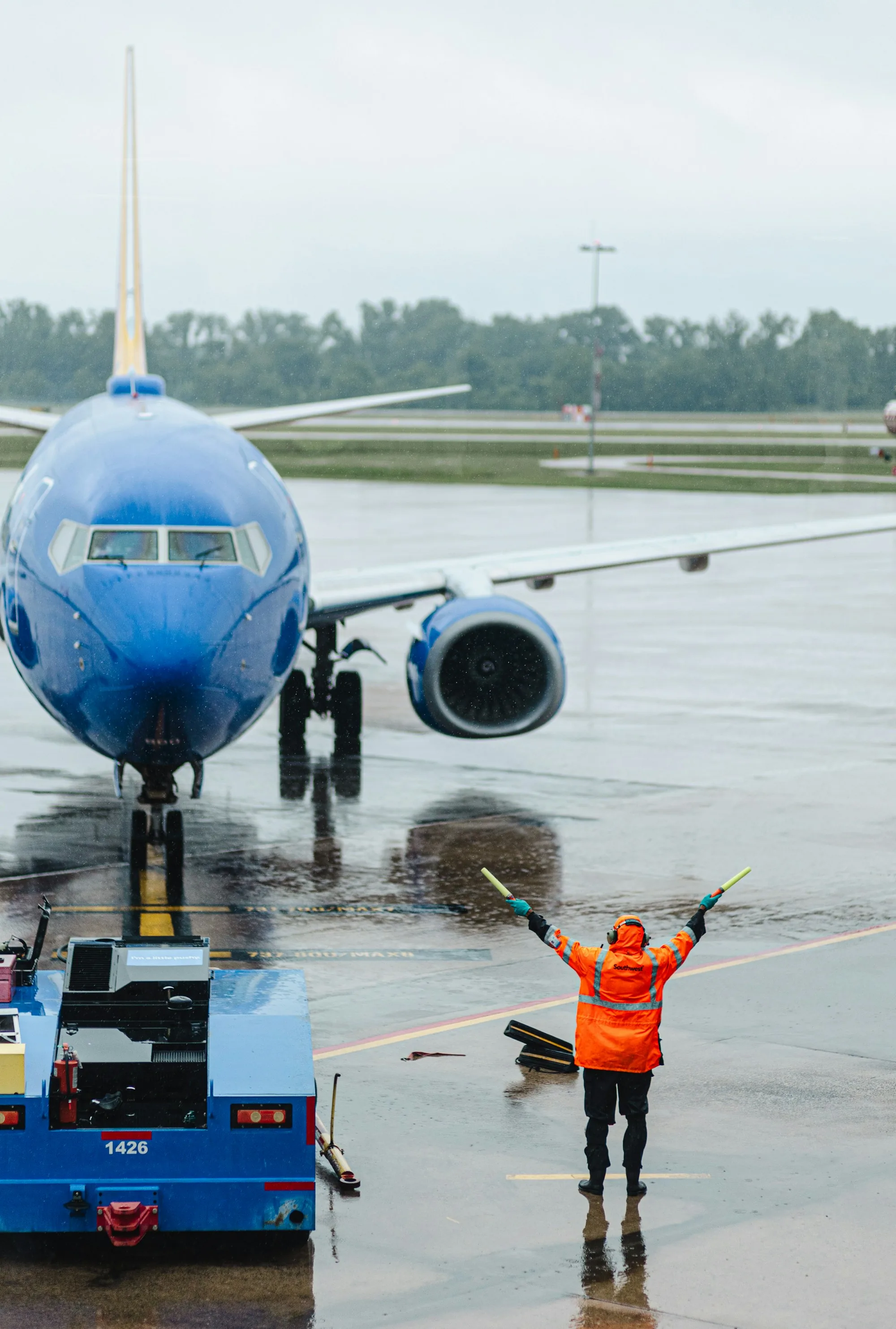 Ground crew member directing an aircraft across an airport apron